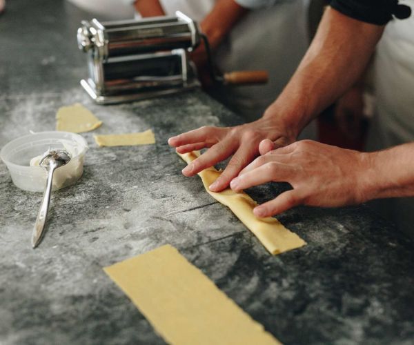 cooks of crocus hill rolling fresh pasta dough on a countertop